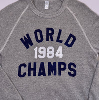 Close up of Heather Gray sweatshirt with 'World Champs 1984' text in navy and white