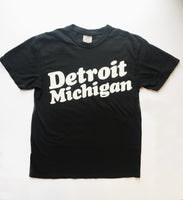 Black T-shirt with Detroit Michigan in big white retro 80s-style text