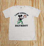 Cream colored t-shirt featuring a retro mickey cartoon character wearing green shorts holding a horseshoe with the text 'I Got Lucky in Detroit' in bold black letters